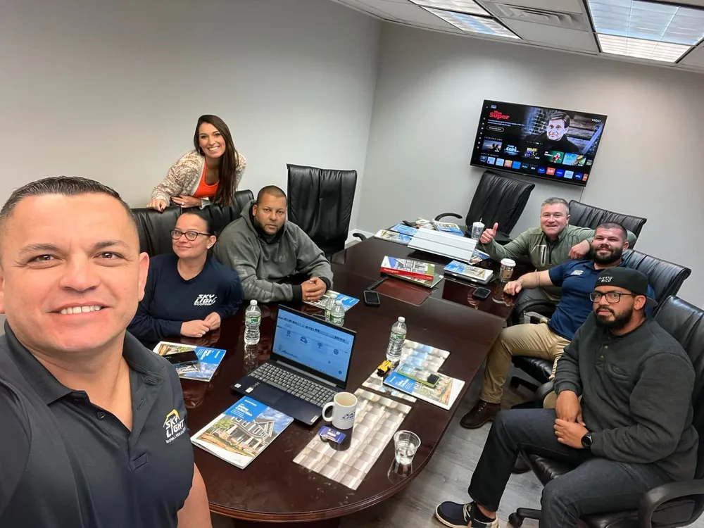 The Skylight Roofing team around the conference table in the office with shingle sample boards and manufacturer literature