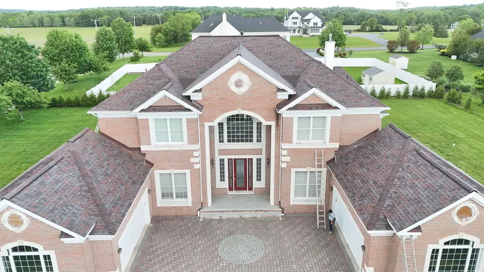 Aerial view of a completed roof replacement on a large brick colonial home in Central New Jersey
