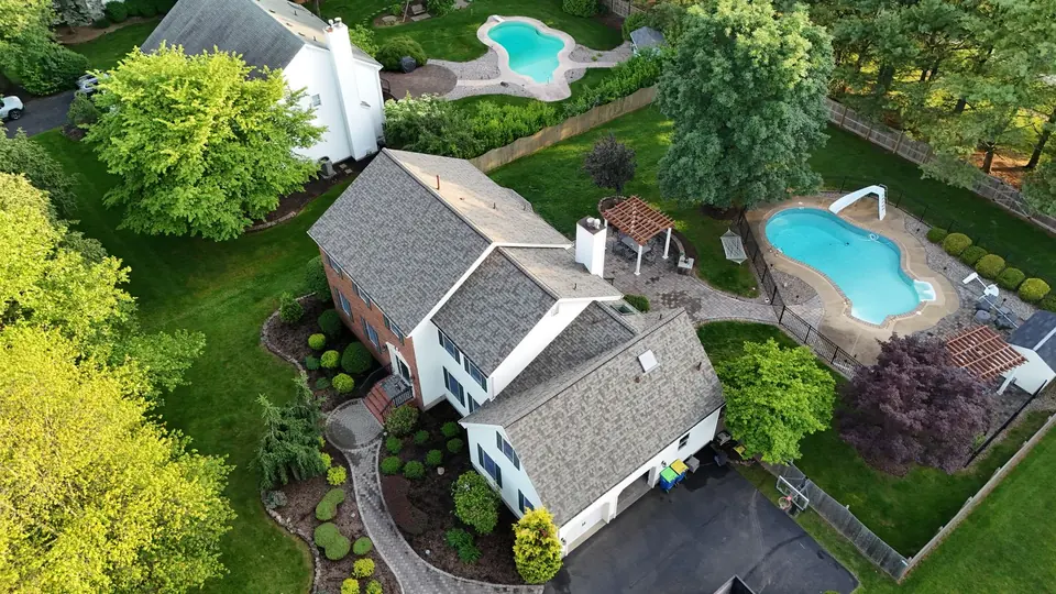 Completed roof replacement on a home with a backyard pool, photographed by drone