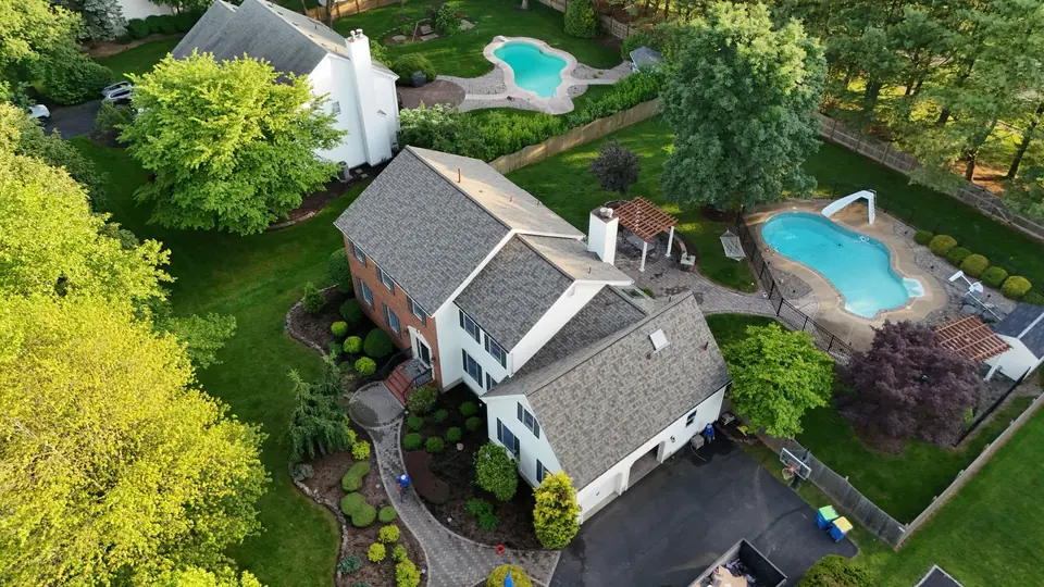 Aerial view of a finished roof on a home with a pool and landscaped grounds