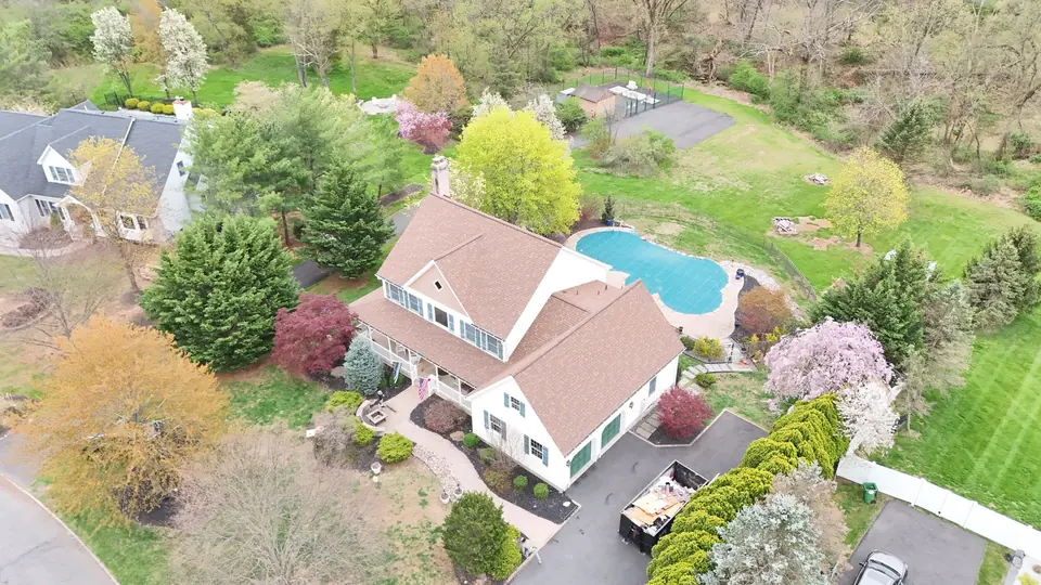 Wide aerial of a completed roof on a home with a pool and flowering trees