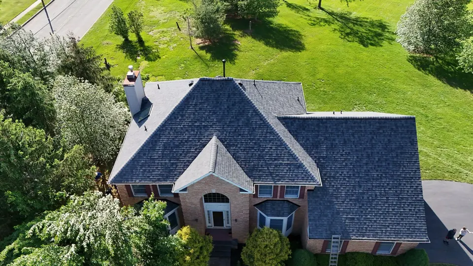 Deep charcoal shingle roof on a brick home, photographed after the final inspection