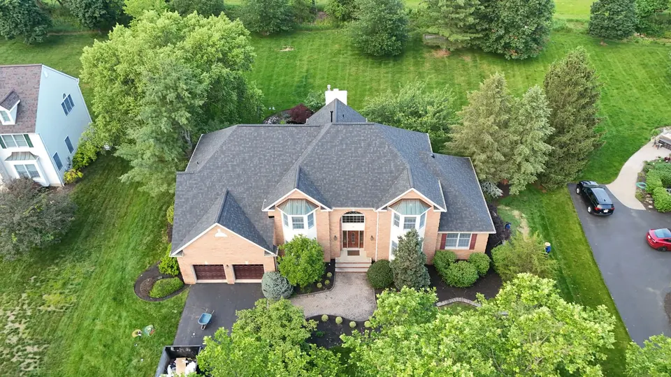 Completed shingle roof on a home with a circular driveway, drone photo