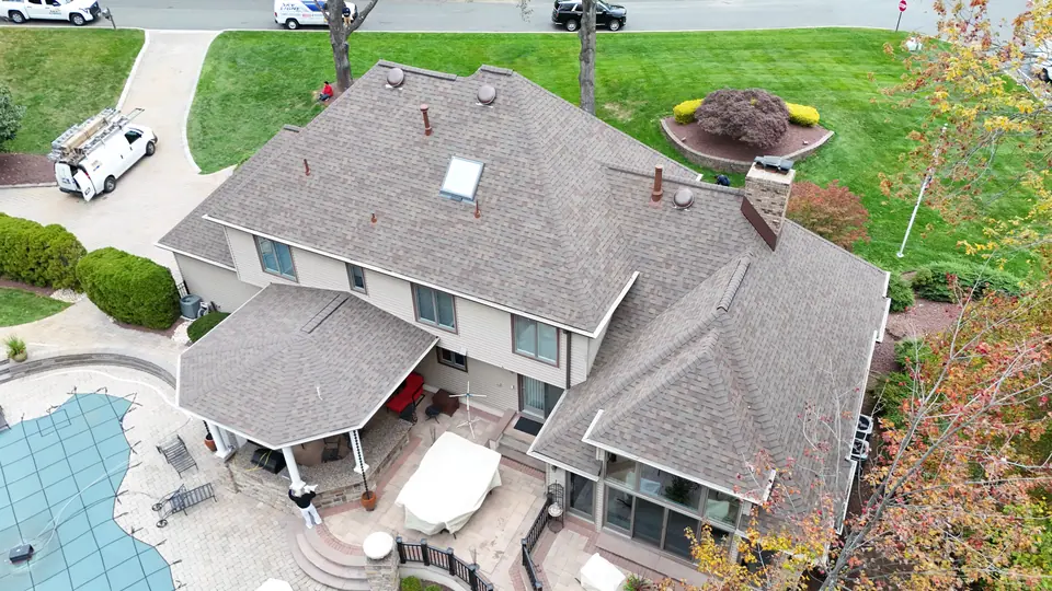 Finished weathered wood shingle roof with a skylight on a large home with a pool and covered patio, autumn drone photo