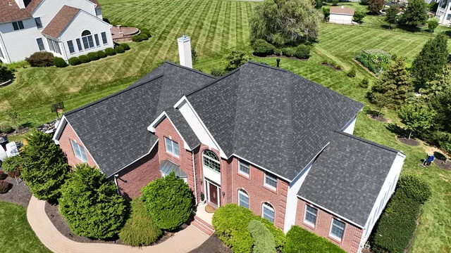 Finished charcoal shingle roof on a red brick colonial home, photographed by drone